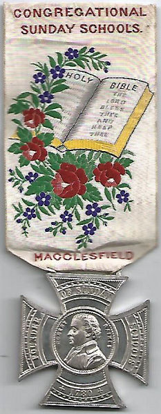 ribbon with words, image of bible and medal attached at pointed end