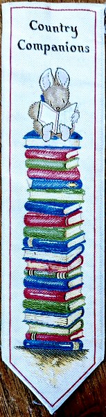 Cash's woven bookmark with woven title words, and image of a rabbit sat on a stack of books, reading