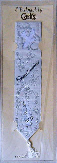 J & J Cash woven bookmark, with title words and image of a champagne bottle, trimmed in silver