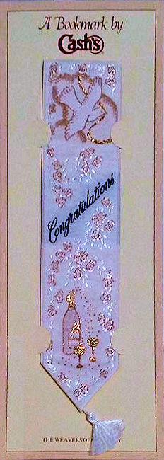 J & J Cash woven bookmark, with title words and image of a champagne bottle, trimmed in gold