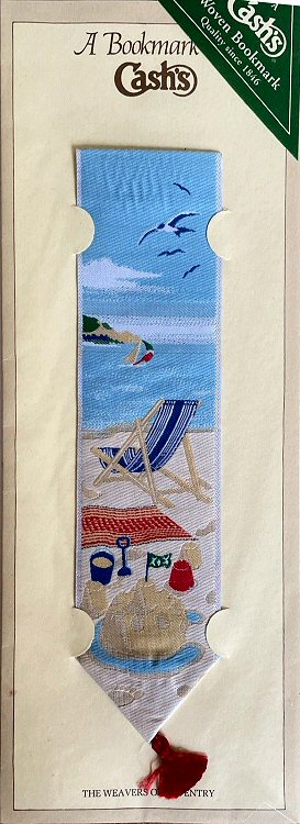 Cash's woven bookmark with no words, just view of a sandy beach with a blue deck chair